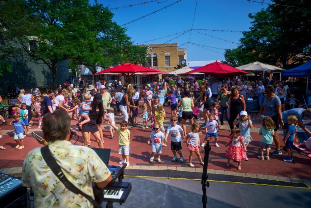 Outdoor summer event with people dancing on plaza.