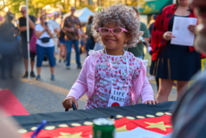 Child in costume with gray wig and glasses.