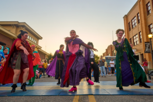 People dancing in colorful costumes on street
