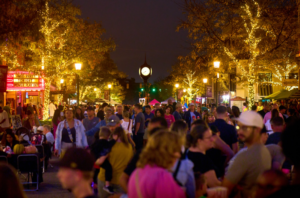 Crowded festival street lit with festive lights.