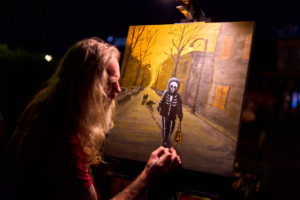 Artist painting spooky street scene at night